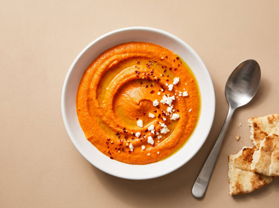 Paprika-Feta-Dip mit Olivenöl und Chiliflocken in einer weissen Schale