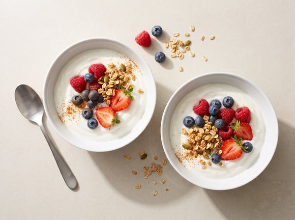 Zwei Skyr-Bowls mit Himbeeren, Heidelbeeren, Erdbeeren und Knusperflocken